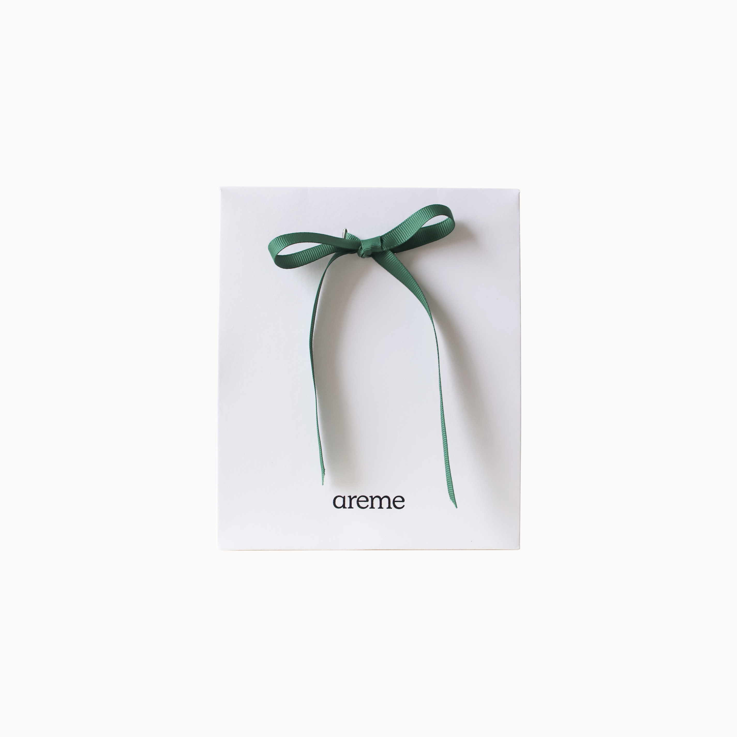 Green ribbon on a white gift bag with 'areme' branding