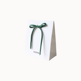 White gift bag with a green ribbon and 'areme' branding on a white background